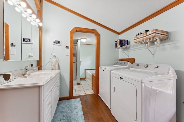 clothes washing area featuring washing machine and dryer, a textured ceiling, crown molding, hardwood / wood-style flooring, and sink