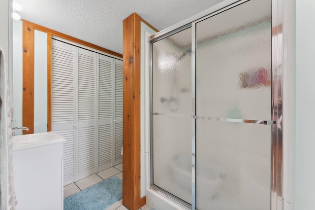 bathroom featuring vanity, a shower with shower door, a textured ceiling, and tile patterned floors