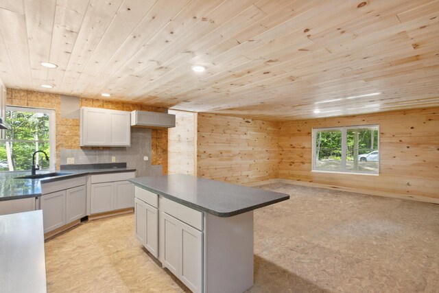 kitchen with wood walls, wood ceiling, a kitchen island, and a wealth of natural light