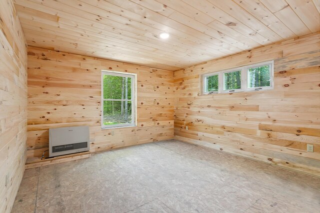 unfurnished living room with wood ceiling, wood walls, heating unit, and plenty of natural light