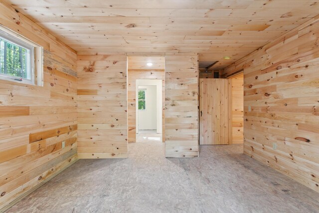 unfurnished room with wood ceiling, wooden walls, and a healthy amount of sunlight