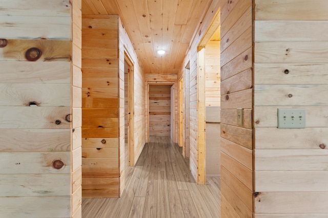 hallway featuring wooden walls, light hardwood / wood-style floors, and wooden ceiling