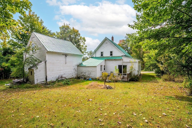 rear view of property with an outdoor structure, a lawn, metal roof, and a chimney