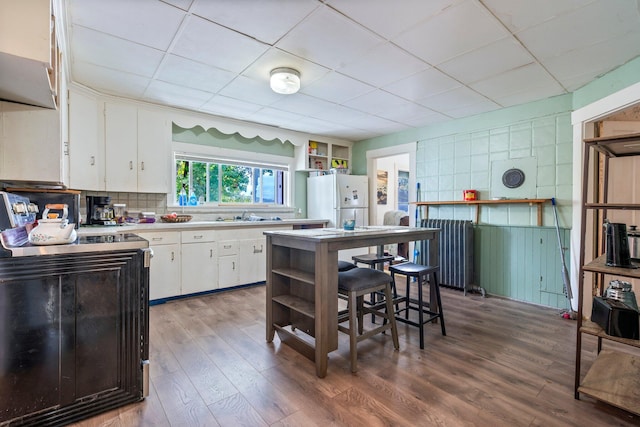 kitchen featuring wood-type flooring, white refrigerator, tasteful backsplash, sink, and white cabinets