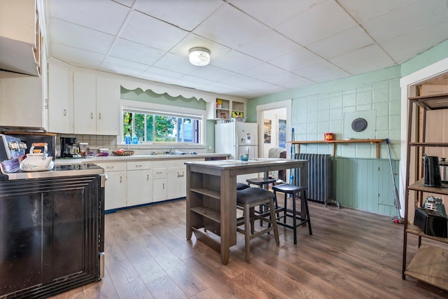 kitchen featuring freestanding refrigerator, light countertops, open shelves, and wood finished floors