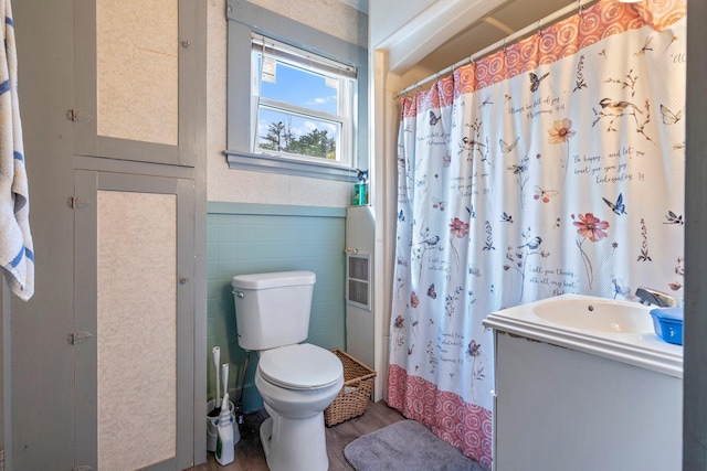 full bathroom with tile walls, toilet, vanity, a shower with curtain, and wainscoting