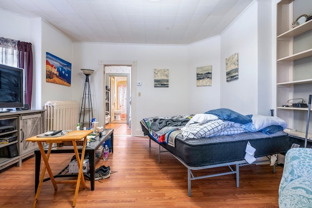 bedroom with crown molding and wood finished floors