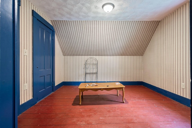 rec room featuring hardwood / wood-style floors, lofted ceiling, and baseboards
