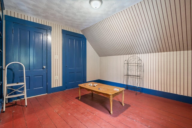 recreation room with baseboards, vaulted ceiling, and hardwood / wood-style flooring