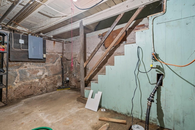 unfinished below grade area featuring electric panel and stairway