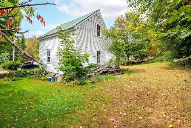 view of side of home featuring a lawn and metal roof