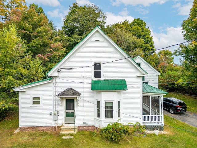 back of property featuring a lawn and a sunroom