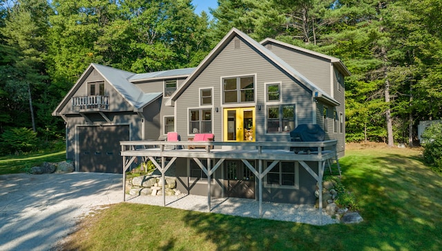 rear view of property with french doors, a balcony, a yard, a garage, and a deck