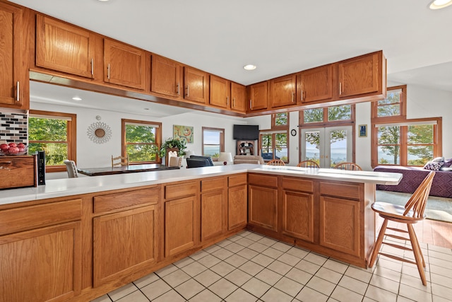 kitchen with kitchen peninsula, plenty of natural light, and light tile patterned floors