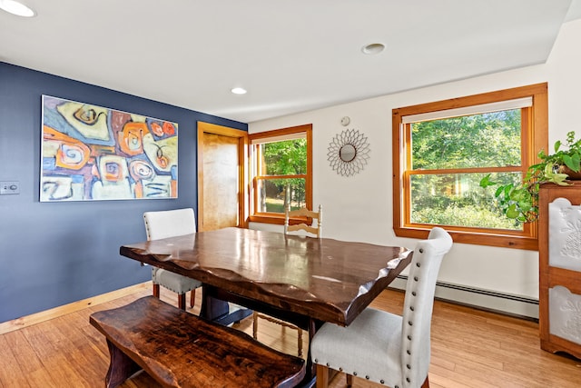 dining room with a healthy amount of sunlight, light hardwood / wood-style floors, and a baseboard heating unit