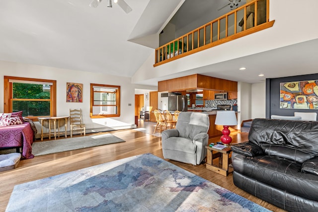 living room featuring ceiling fan, light hardwood / wood-style floors, and high vaulted ceiling