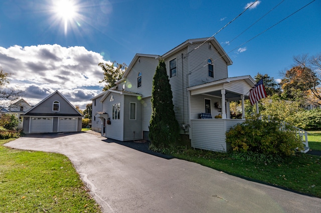 view of front of property featuring a garage, a front lawn, covered porch, and an outbuilding