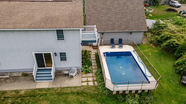 rear view of property with a pool side deck, a lawn, and a patio