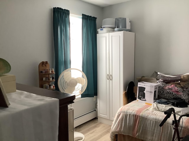 bedroom with light wood-type flooring and a baseboard heating unit