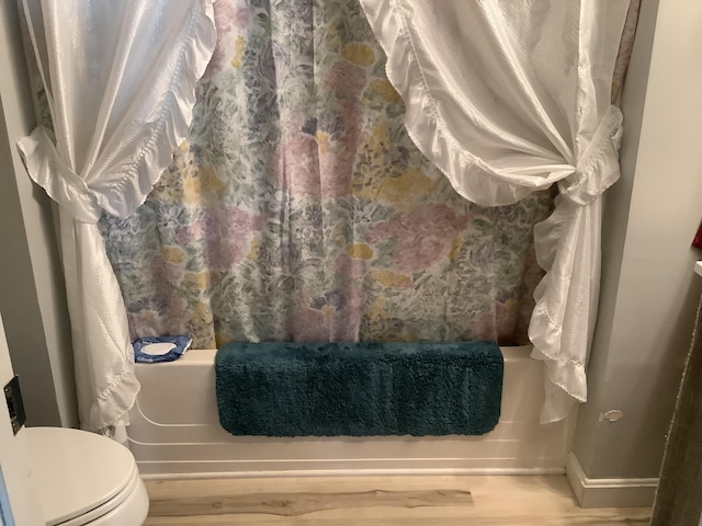 bathroom featuring hardwood / wood-style flooring, toilet, and shower / tub combo