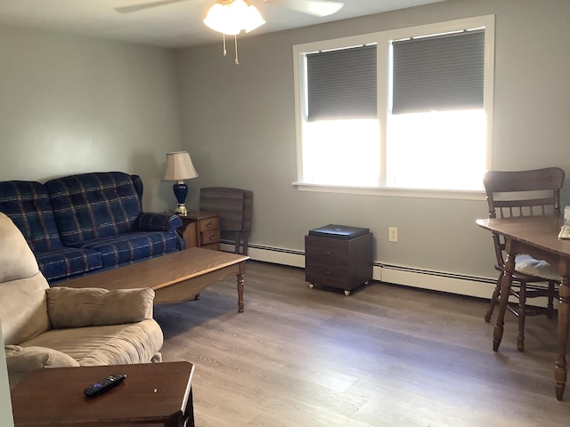 living room featuring baseboard heating, ceiling fan, and light hardwood / wood-style floors