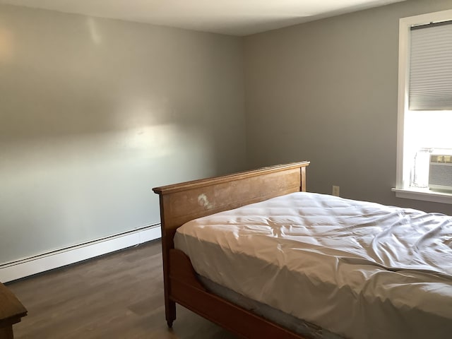 bedroom with dark hardwood / wood-style flooring and a baseboard heating unit