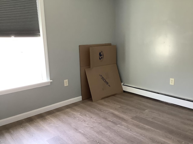 empty room with light hardwood / wood-style floors and baseboard heating