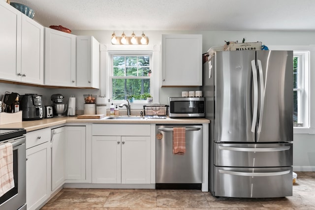 kitchen featuring a textured ceiling, white cabinetry, sink, and stainless steel appliances