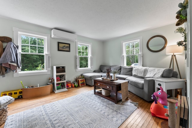 living room featuring a textured ceiling, hardwood / wood-style flooring, a wall unit AC, and plenty of natural light