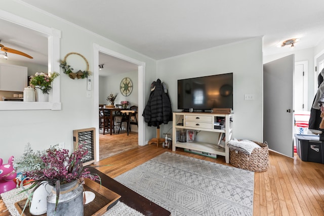 living room featuring crown molding, hardwood / wood-style floors, and ceiling fan