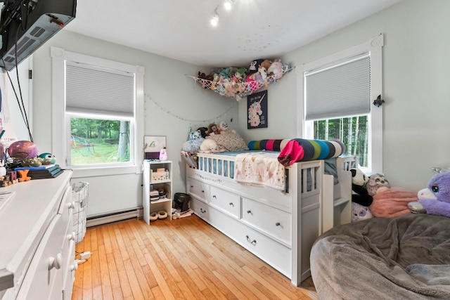 bedroom with light hardwood / wood-style flooring and a baseboard heating unit