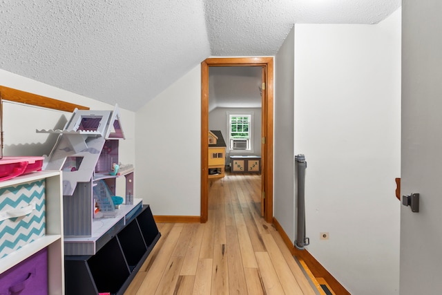 interior space with wood-type flooring, cooling unit, a textured ceiling, and lofted ceiling