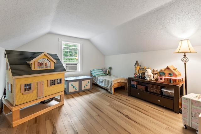 bedroom with a textured ceiling, cooling unit, light hardwood / wood-style floors, and vaulted ceiling