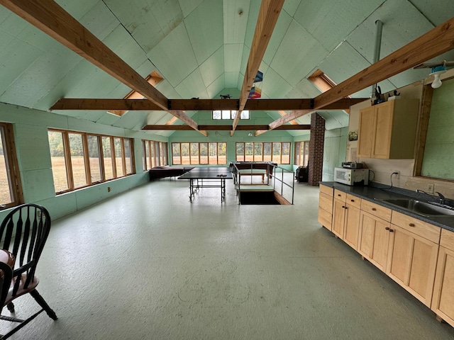 kitchen featuring vaulted ceiling with beams, light brown cabinetry, and sink