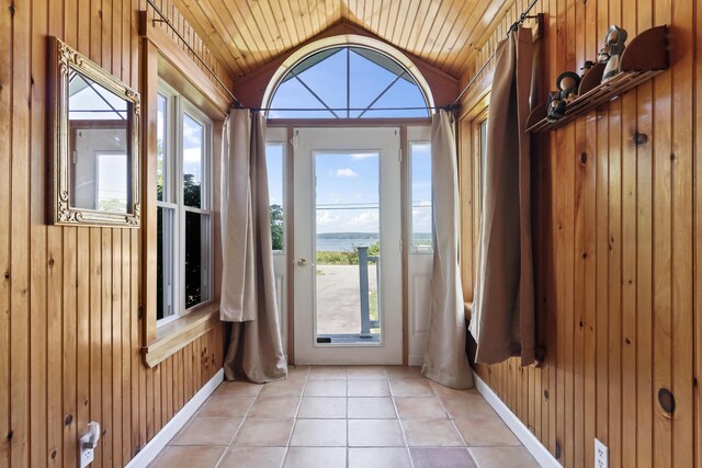 entryway featuring wooden ceiling, lofted ceiling, wooden walls, and light tile patterned flooring