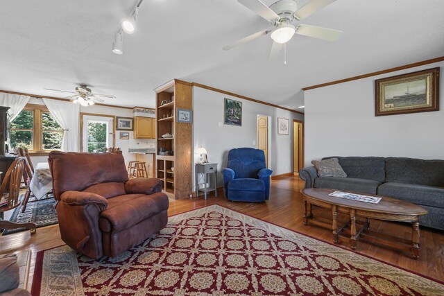 living room featuring ornamental molding, light wood-type flooring, and ceiling fan