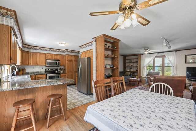 dining area featuring light hardwood / wood-style floors, ceiling fan, track lighting, and sink