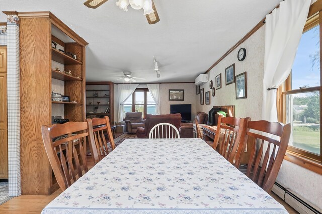 dining space with an AC wall unit, ceiling fan, light hardwood / wood-style flooring, ornamental molding, and a baseboard heating unit