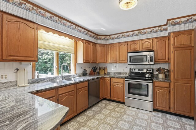 kitchen with stainless steel appliances, sink, dark stone counters, and decorative backsplash