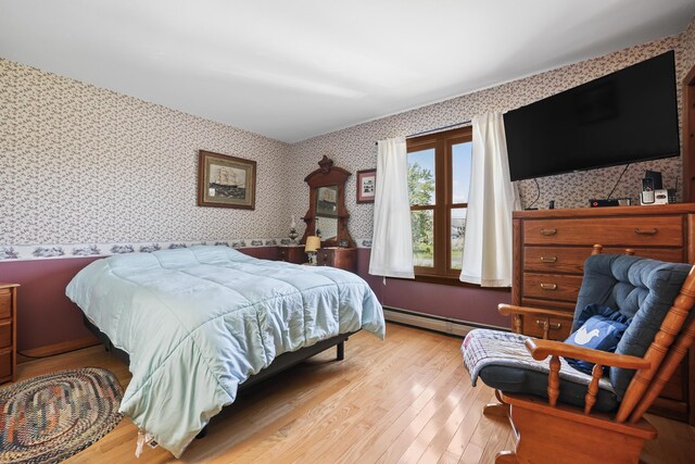 bedroom with baseboard heating and light hardwood / wood-style flooring