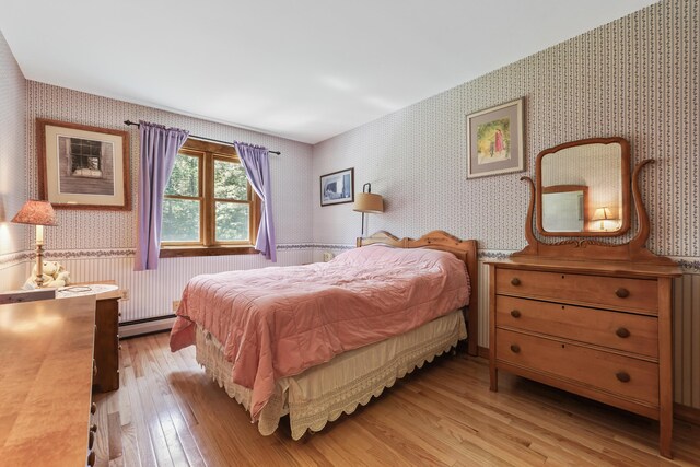 bedroom featuring light hardwood / wood-style floors and a baseboard heating unit