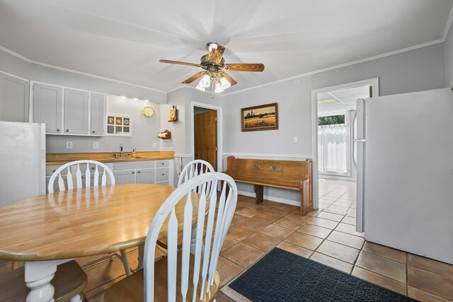 tiled dining room featuring ornamental molding, ceiling fan, and sink