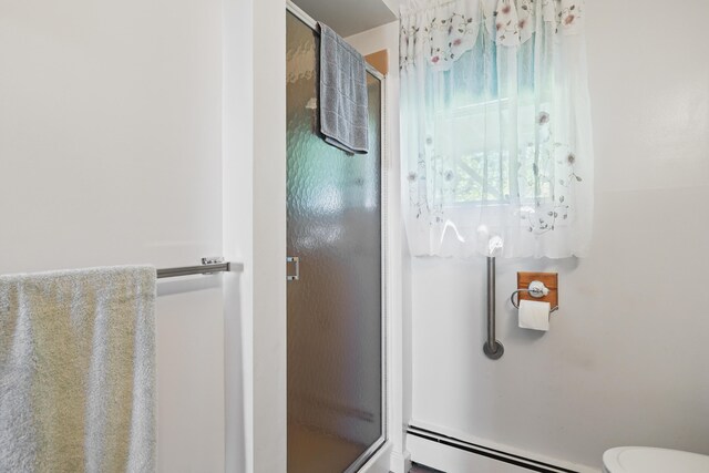 bathroom with a baseboard heating unit, a shower with shower door, and toilet