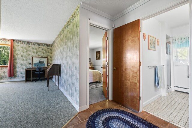 corridor featuring a textured ceiling, carpet, baseboard heating, and a wealth of natural light