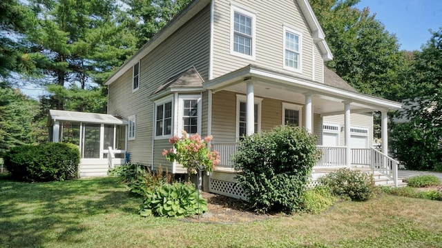 view of side of property with a lawn, covered porch, and a garage