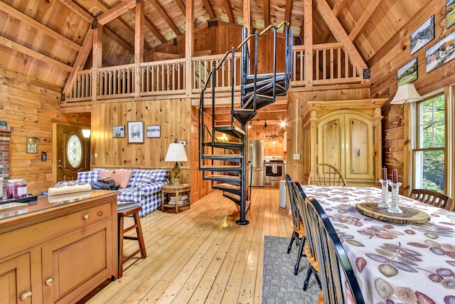 unfurnished dining area featuring wood walls, light hardwood / wood-style floors, wood ceiling, high vaulted ceiling, and beamed ceiling