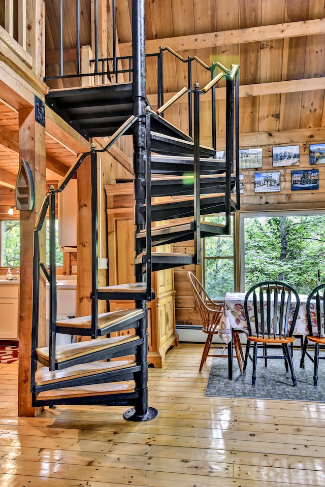 stairway featuring hardwood / wood-style flooring, wood walls, and plenty of natural light