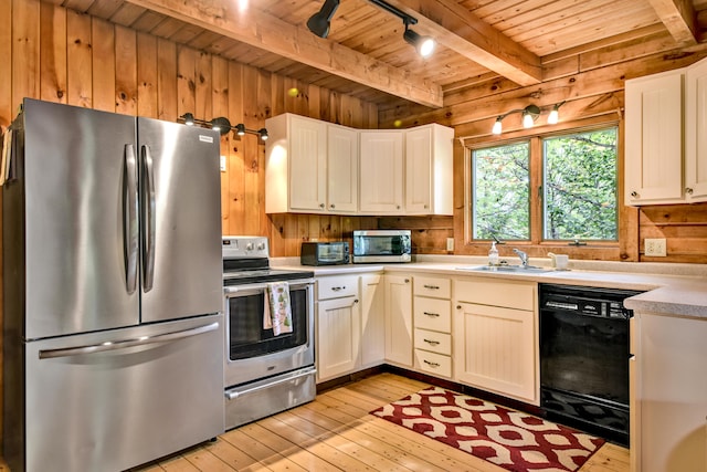 kitchen featuring sink, stainless steel appliances, white cabinets, and wooden walls