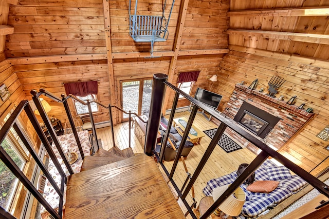 stairway featuring beamed ceiling, wood-type flooring, a baseboard heating unit, wood walls, and wood ceiling