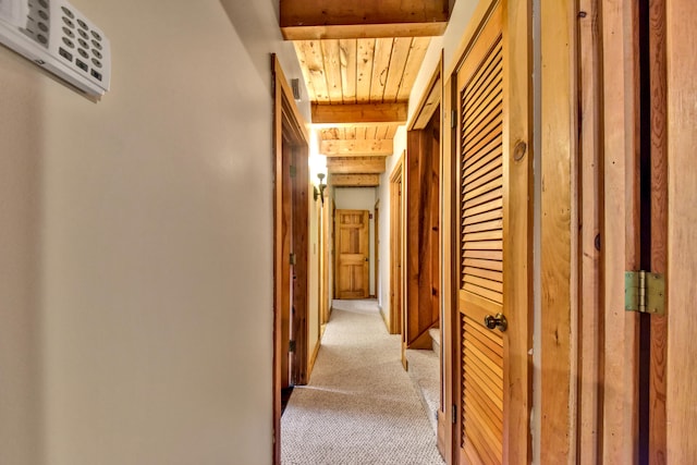 hallway featuring wooden ceiling, beamed ceiling, and light colored carpet